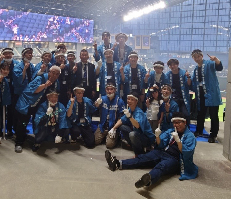 23年のエスコンフィールド1勝目を喜ぶ闘将会と小村社長（中列右から6人目）（闘将会提供）