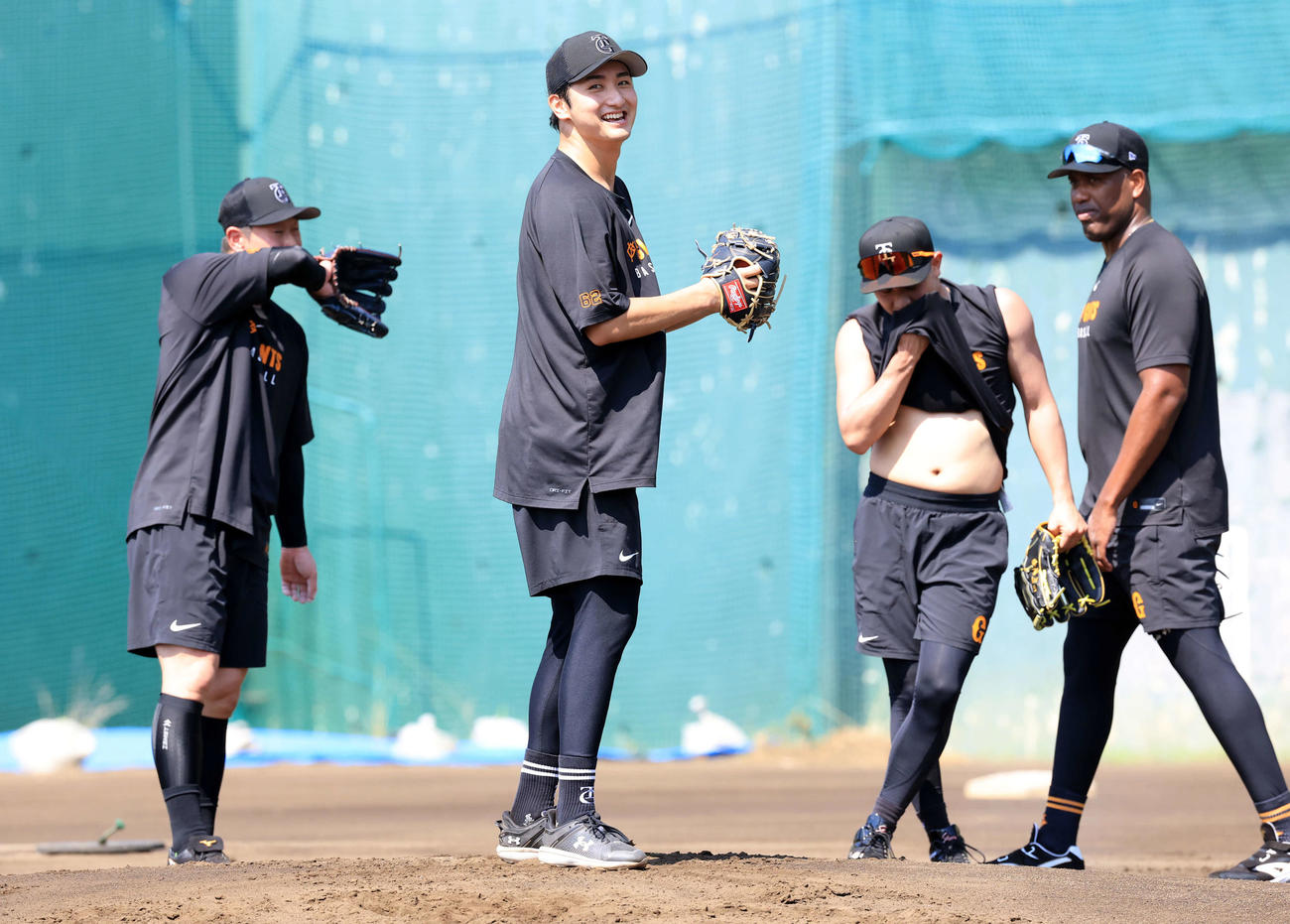 25年7月25日　炎天下のノックで、汗をぬぐう選手の中でさわやかな笑顔を見せる巨人横川（中央）（撮影・浅見桂子）