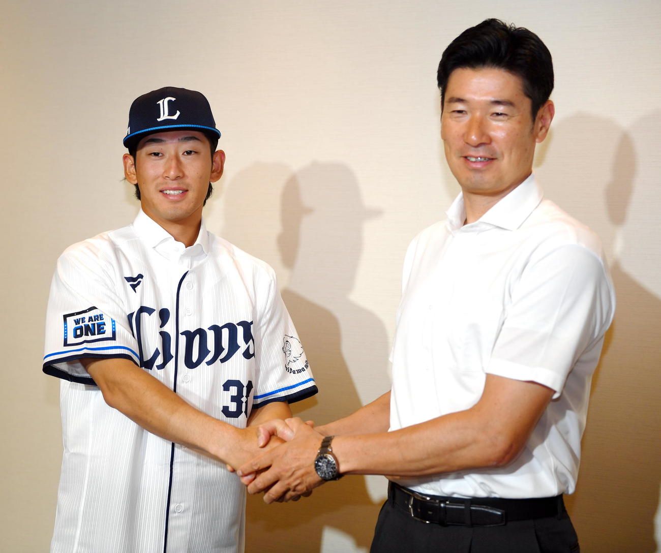支配下登録され握手する西武佐藤太（左）と広池球団本部長（撮影・山田愛斗）