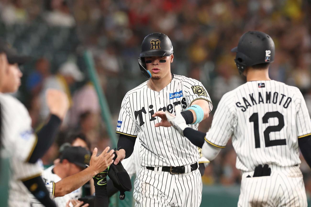 阪神対DeNA 7回裏阪神1死一、二塁、大山の2点適時二塁打で生還しナインとハイタッチをする佐藤輝（撮影・上田博志）
