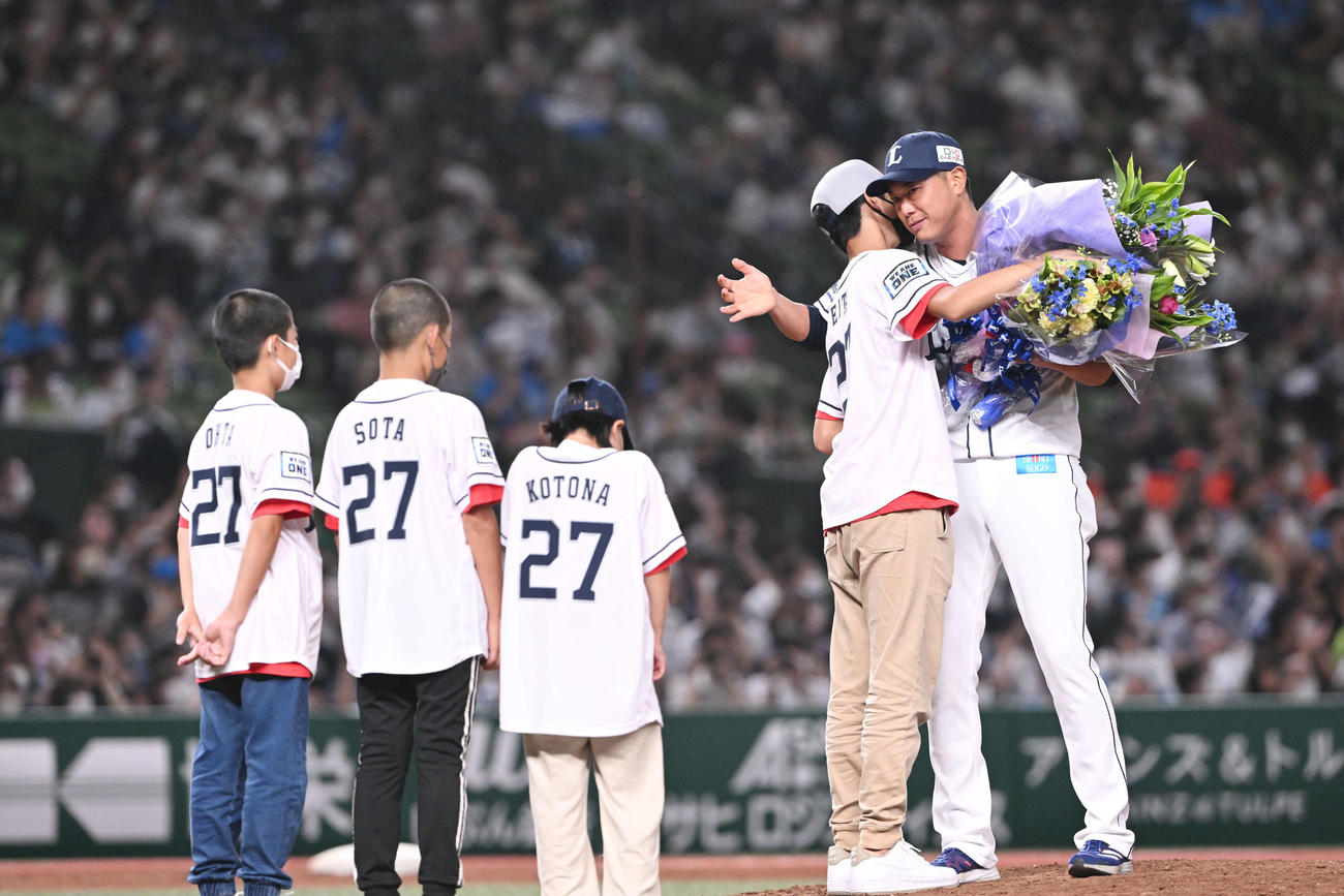 22年9月19日　西武対楽天　引退セレモニーで西武内海（右）は子どもたちから花束を受け取り抱き締める（撮影・滝沢徹郎）