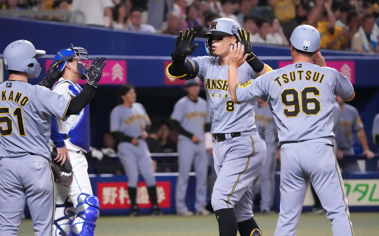 中日対阪神　8回表阪神無死一、二塁、佐藤輝（中央）は右中間へ3点本塁打を放ち生還しナインとタッチ（撮影・森本幸一）