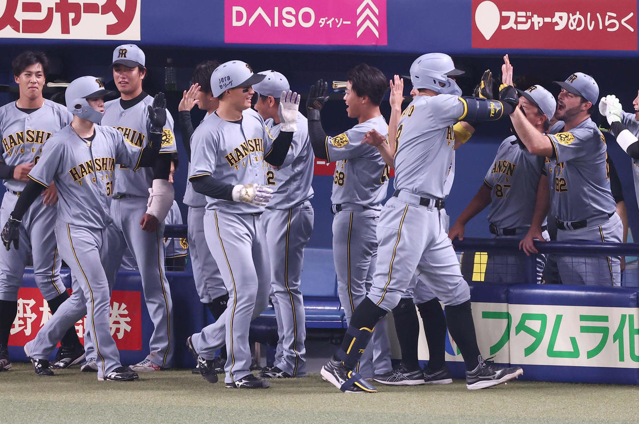 中日対阪神　8回表中日無死一、二塁、逆転3点本塁打を放った佐藤輝（右から2人目）はハートウィグ（右）らナインとハイタッチをする（撮影・上田博志）