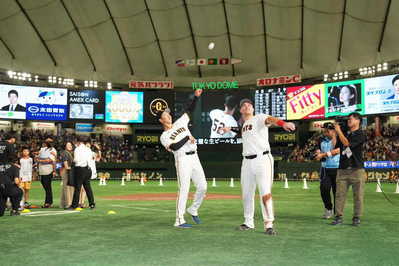 巨人対ヤクルト　ファンにボールを投げ入れる巨人のプロ初勝利の森田（左）とリチャード（撮影・足立雅史）