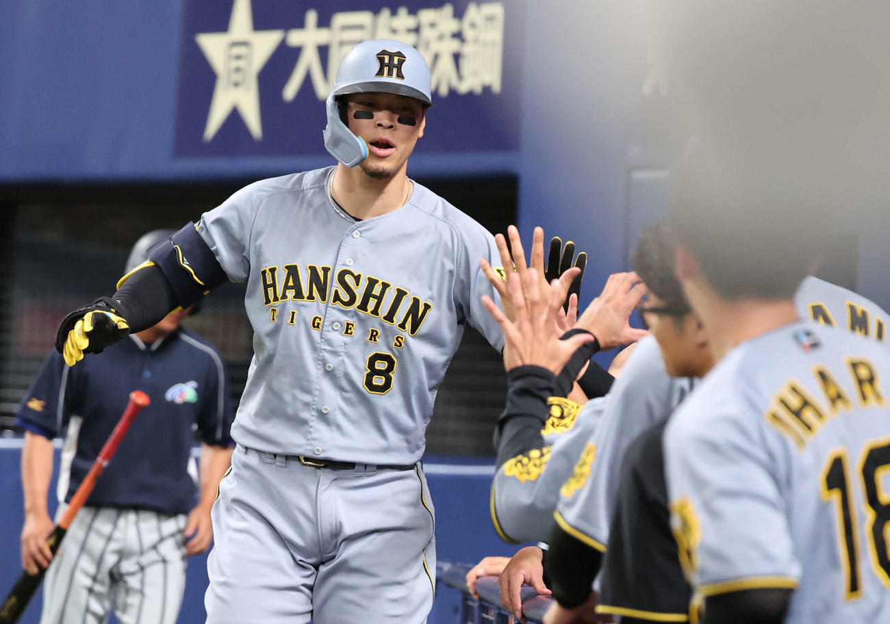 中日対阪神　4回表阪神無死、佐藤輝は中越えに本塁打を放ち、ベンチ前で祝福を受ける（撮影・西尾就之）