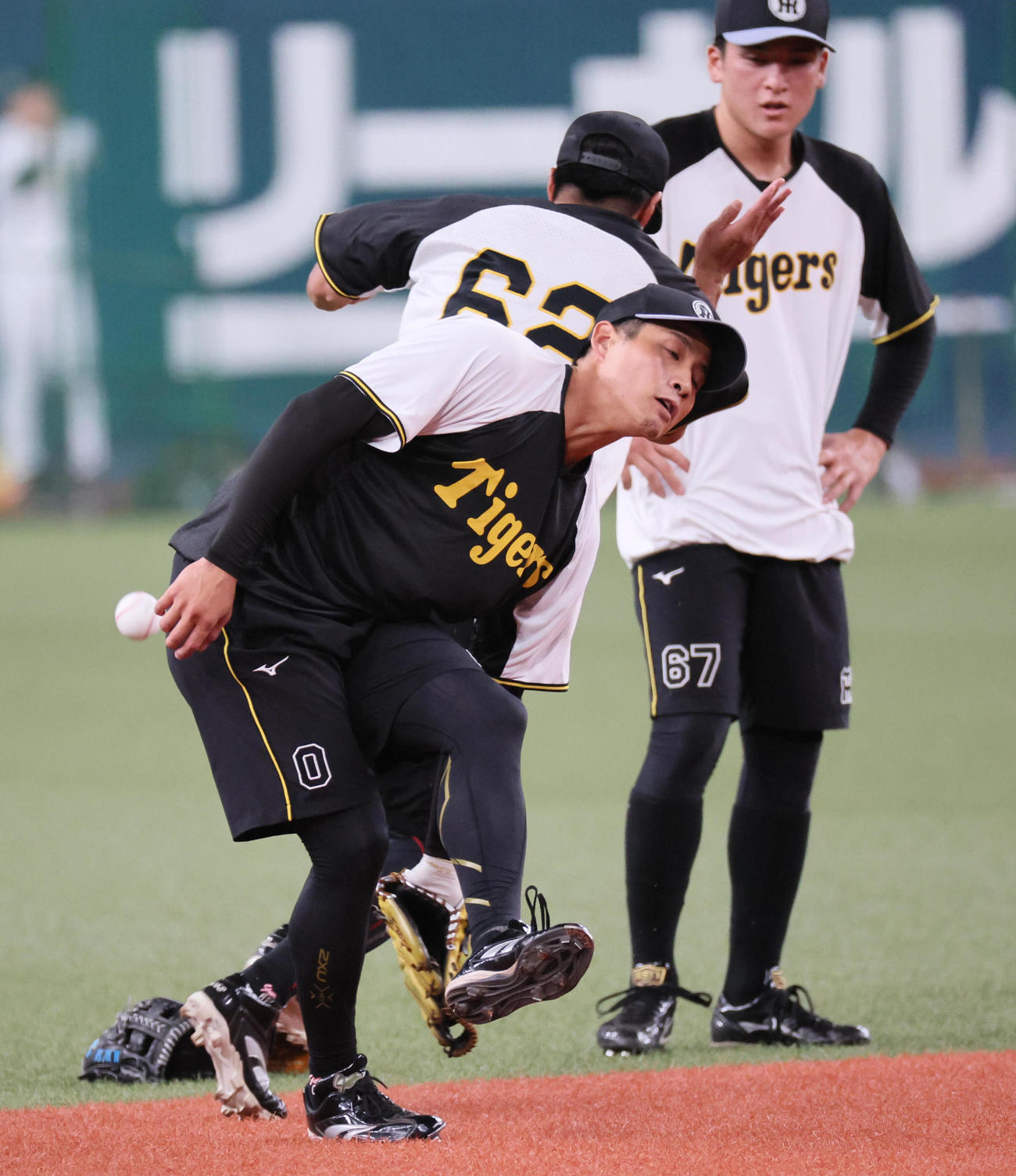 阪神対ヤクルト　ノックを受けていた木浪（手前）のグラブの下をすり抜けたフリー打撃の打球が走塁練習中の植田の足に当たる（撮影・宮崎幸一)