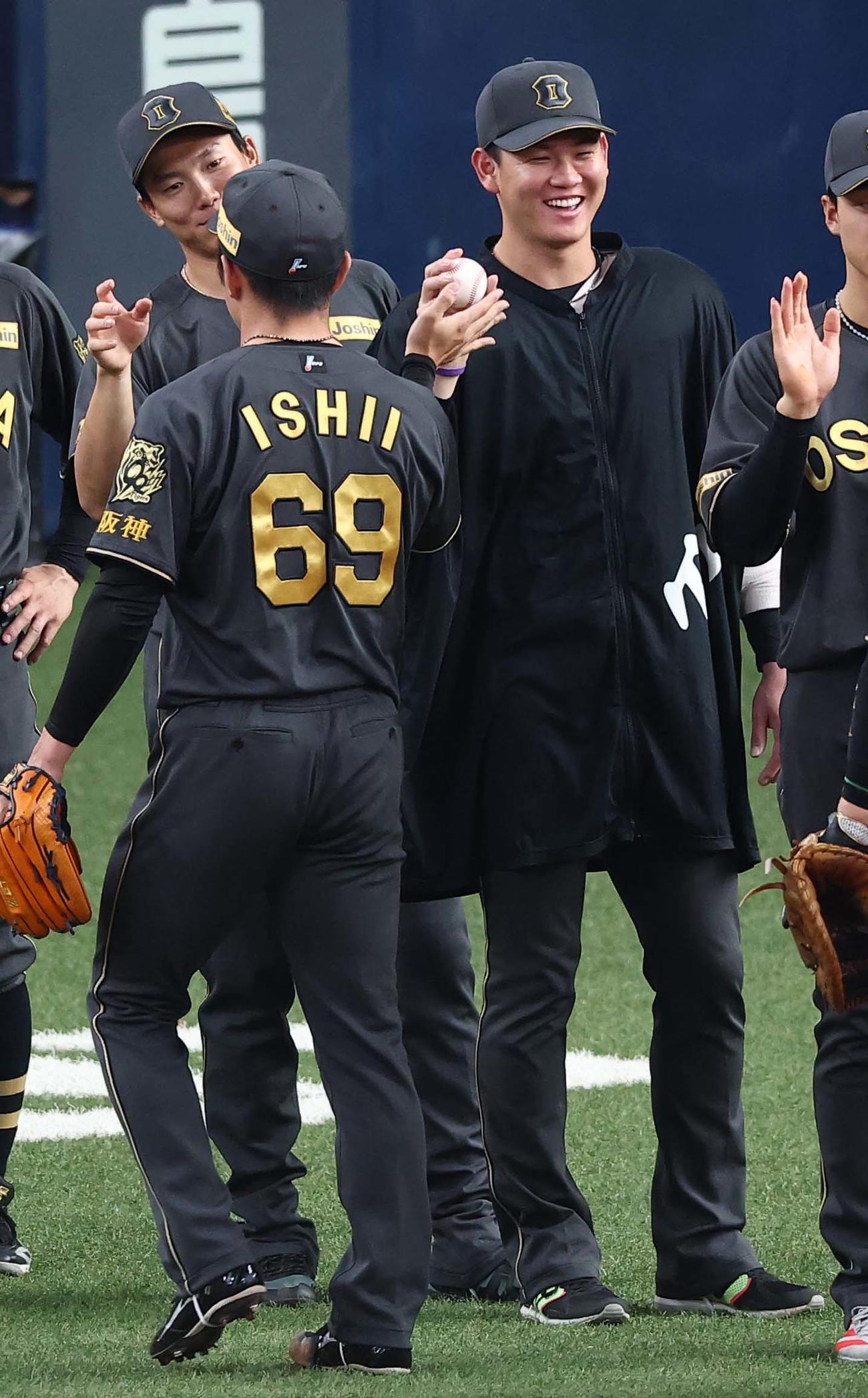 阪神対ヤクルト　6勝目をあげた及川（右）は石井から勝利球を受け取る（撮影・上田博志）