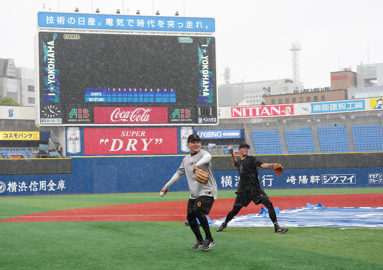 試合前、激しい雨の中、練習する巨人の丸（左）と坂本（撮影・足立雅史）