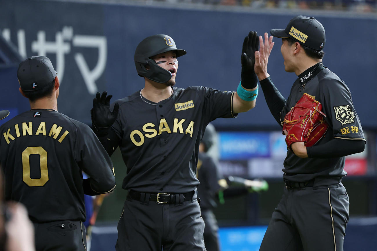 阪神対ヤクルト　3回裏阪神2死、右中間へ31号本塁打を放ち、才木（右）とタッチを交わす佐藤輝（撮影・前田充）