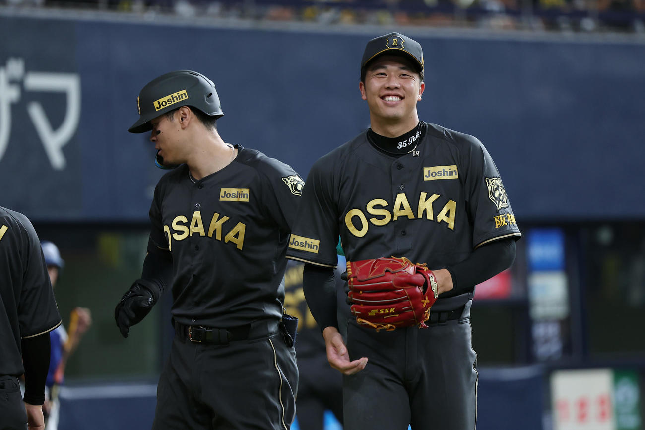 阪神対ヤクルト　3回裏阪神2死、31号本塁打を放った佐藤輝（左）とタッチを交わし、笑顔を見せる才木（撮影・前田充）