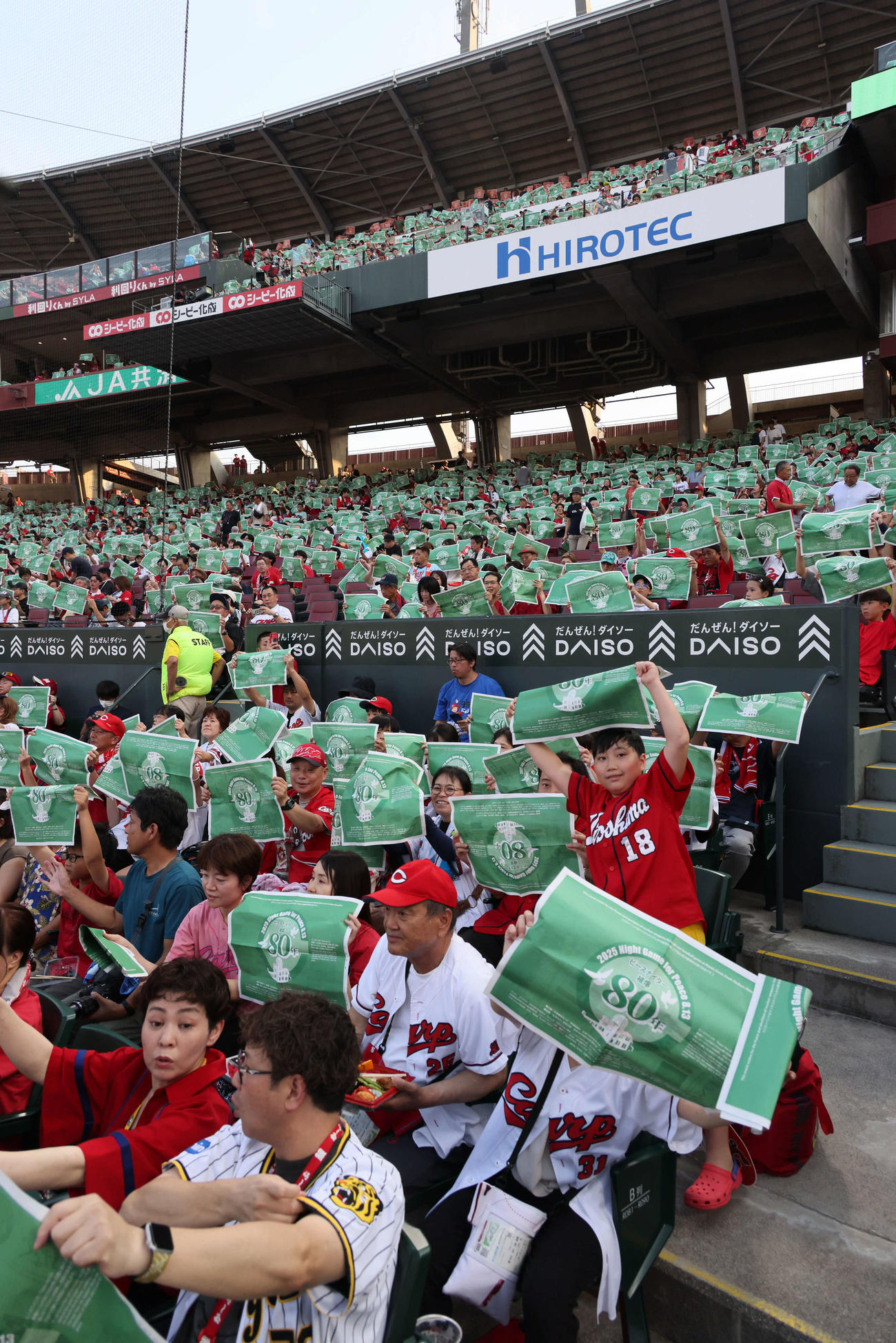 広島対阪神　ピースナイターで緑色の新聞を掲げる観客ら（撮影・加藤孝規）