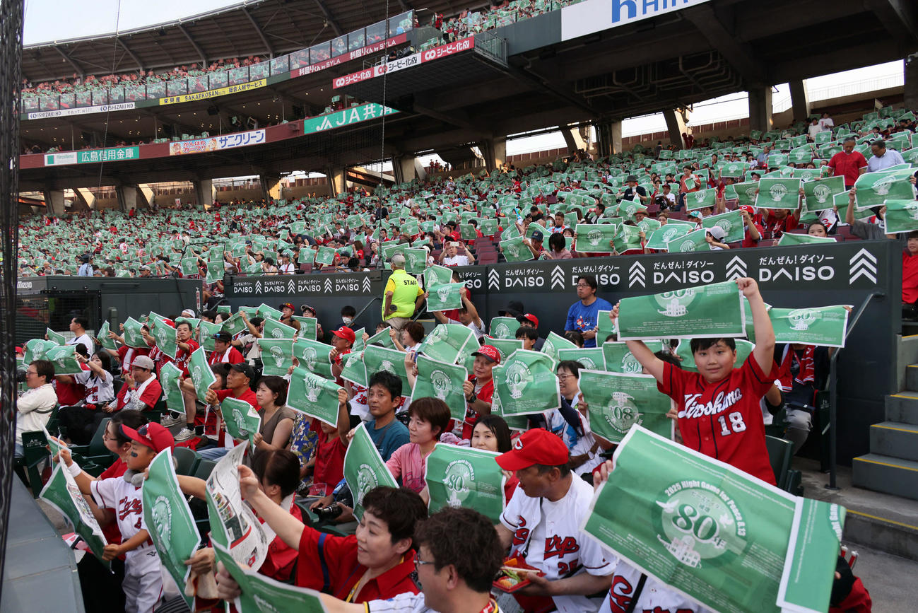 広島対阪神　ピースナイターで緑色の新聞を掲げる観客ら（撮影・加藤孝規）