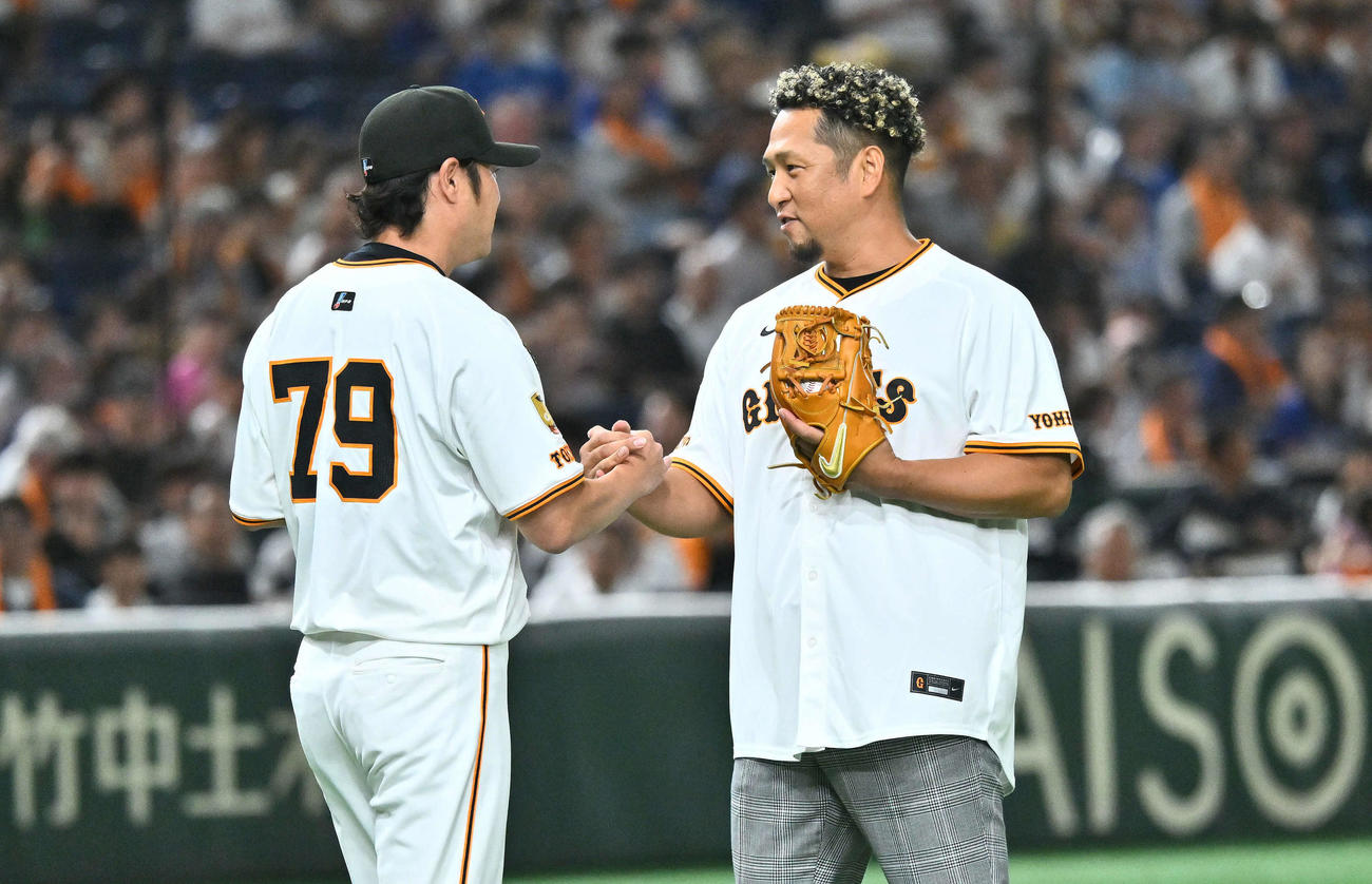 巨人対中日　試合前に行われた自身の引退セレモニーのファーストピッチを終えた中島氏（右）は捕手を務めた巨人亀井コーチと握手を交わす（撮影・滝沢徹郎）