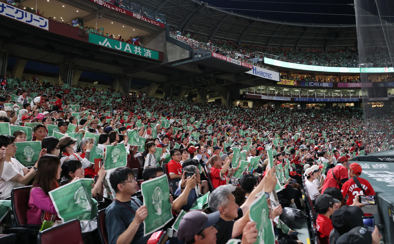 広島対阪神　ピースナイターで緑色の新聞を掲げる観客ら（撮影・加藤孝規）