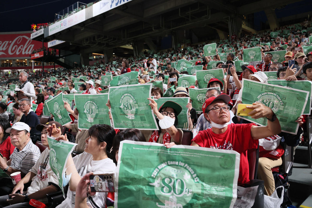 広島対阪神　ピースナイターで緑色の新聞を掲げる観客ら（撮影・加藤孝規）