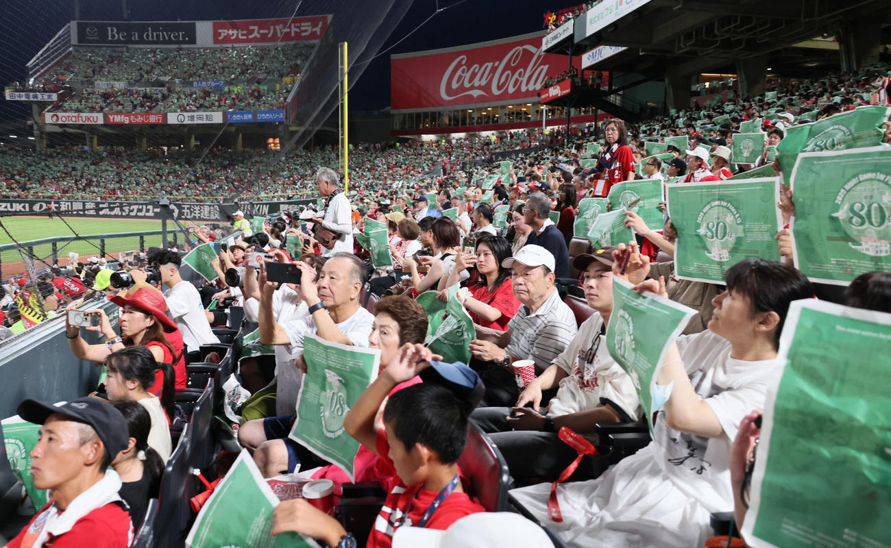 広島対阪神　ピースナイターで緑色の新聞を掲げる観客ら（撮影・加藤孝規）