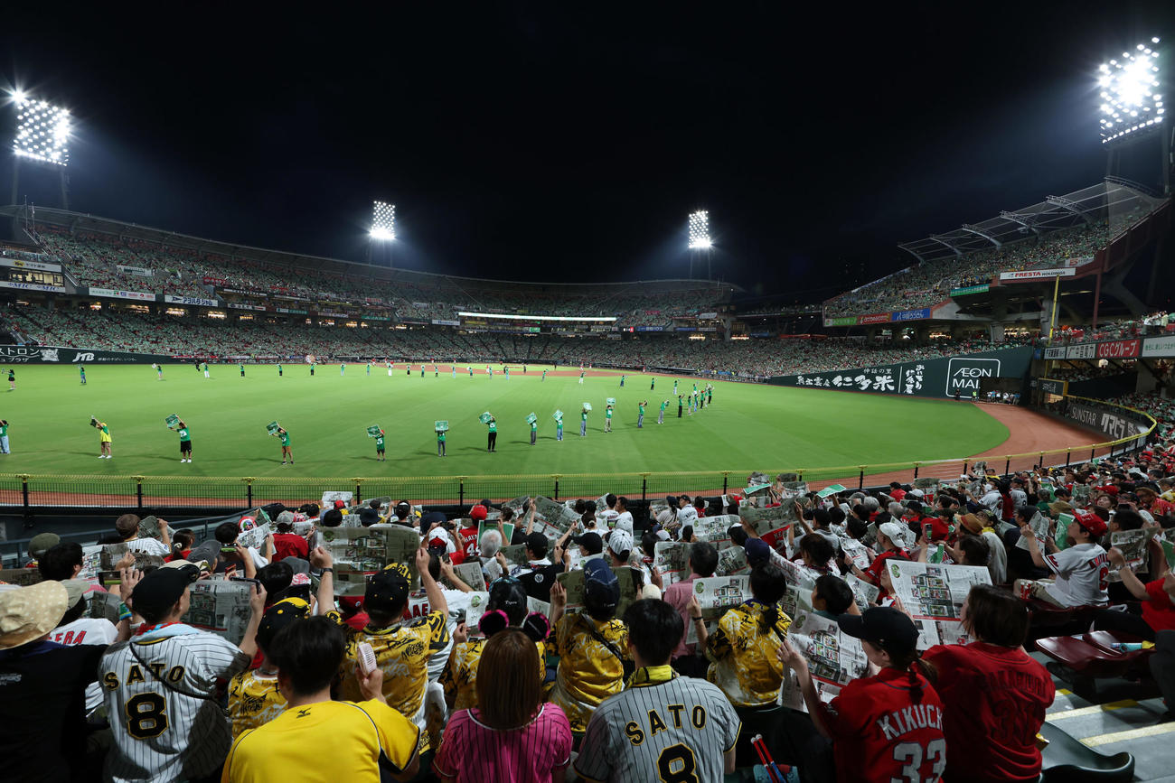 広島対阪神　5回終了後、吉川晃司が歌う「イマジン」に合わせて緑色の新聞を掲げるファンたち（撮影・前田充）