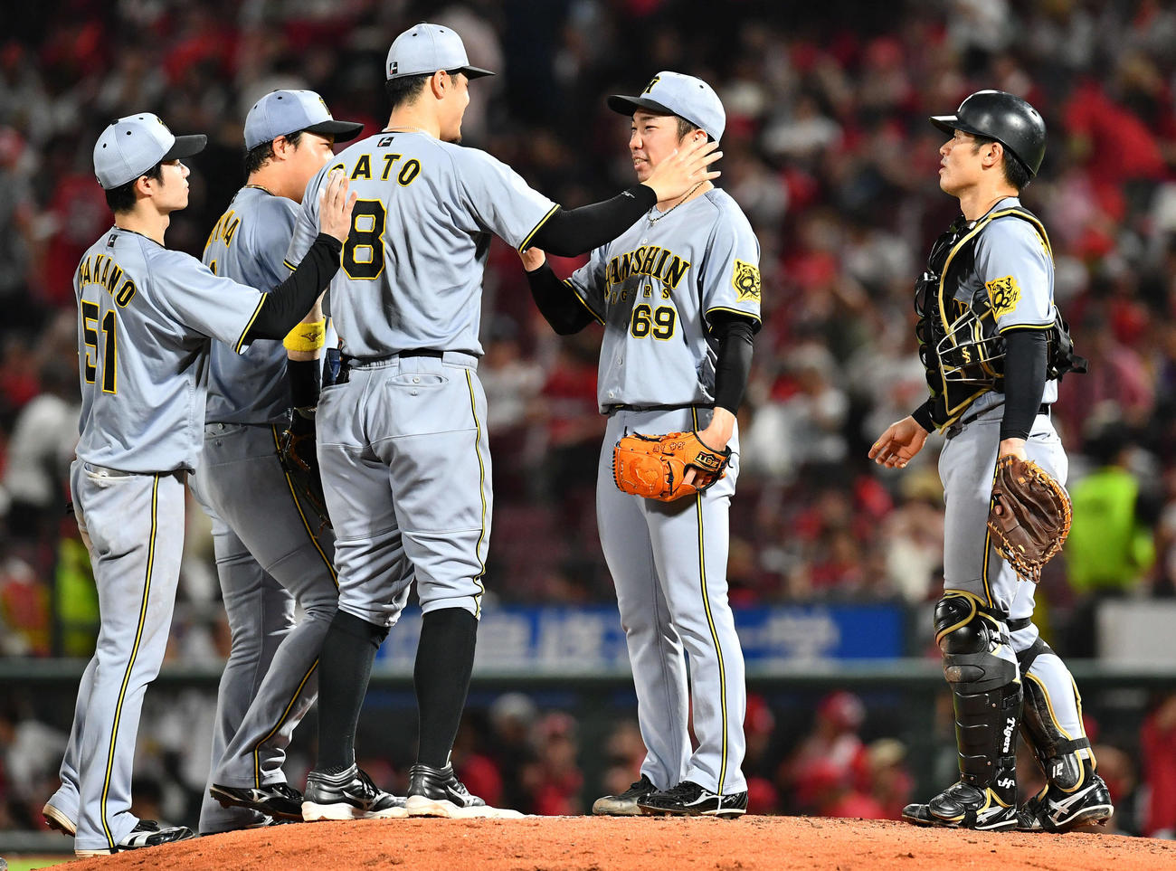 広島対阪神　セリーグ新記録となる39試合連続無失点を達成した石井（右から2人目）は佐藤輝（左から3人目）らナインから祝福される（撮影・岩下翔太）