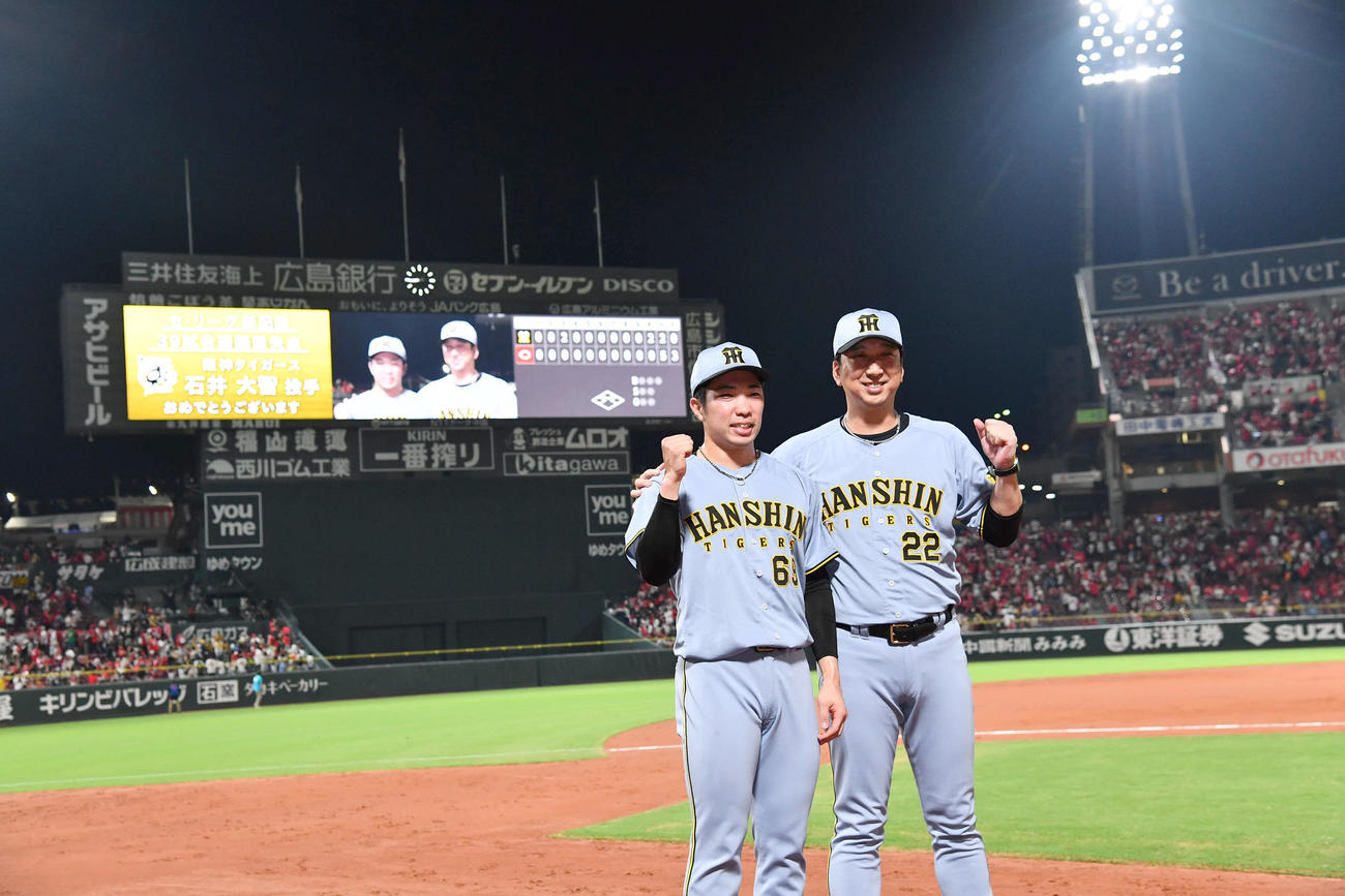 セリーグ新記録となる39試合連続無失点を達成した石井（左）は藤川監督と写真に納まる（2025年8月13日撮影）