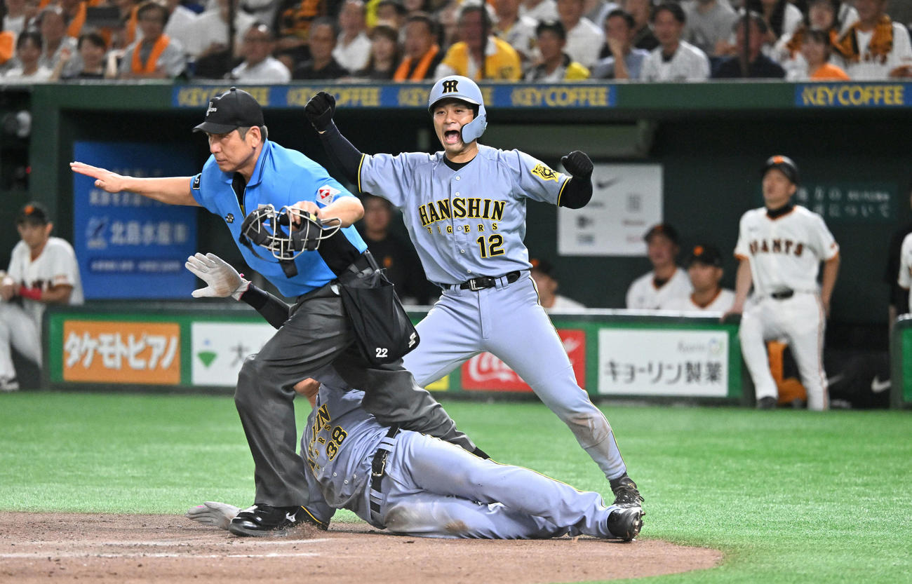 巨人対阪神　4回表阪神2死二、三塁、近本の2点適時打で生還する二塁走者小幡（下）。後方は三塁走者坂本（撮影・滝沢徹郎）