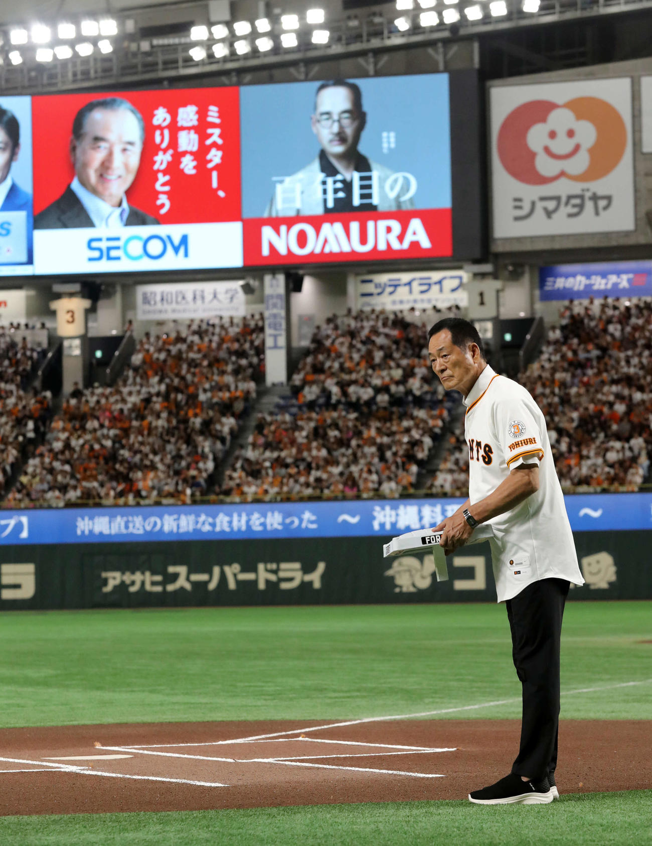 巨人対阪神　長嶋茂雄終身名誉監督追悼試合で笑顔の看板を背に三塁ベースを運ぶ中畑清氏