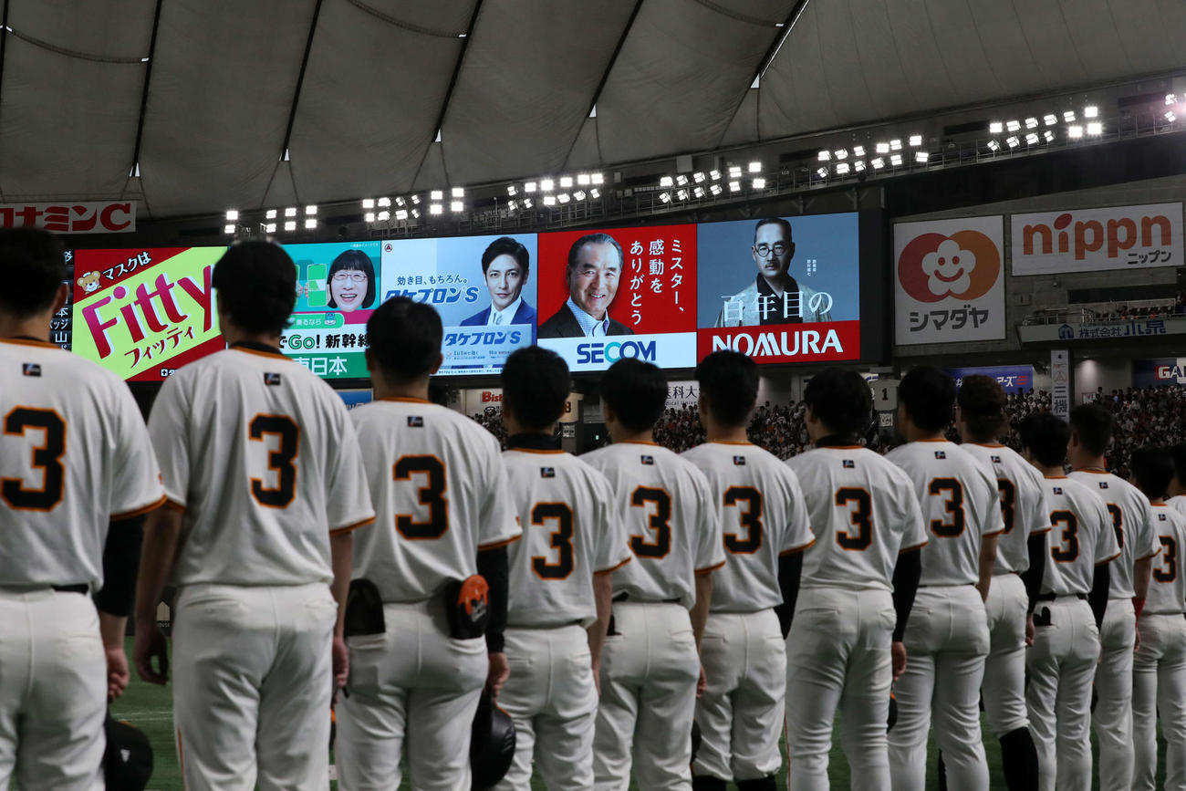 巨人対阪神　長嶋茂雄終身名誉監督追悼試合で笑顔の看板に向い、背番号3をつけて君が代斉唱する巨人の選手たち