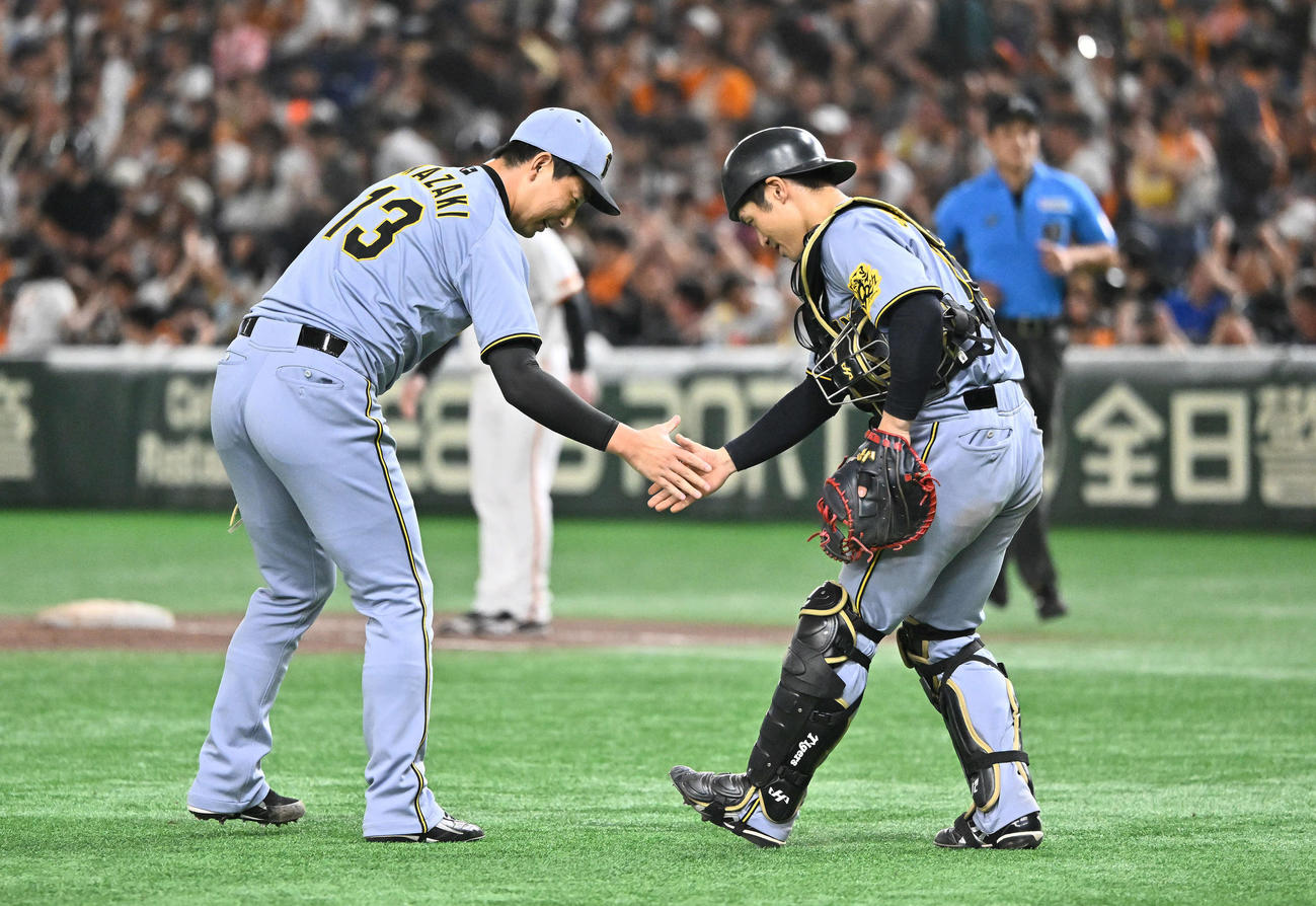 巨人対阪神　9回裏巨人2死一、二塁、代打坂本を空振り三振に仕留めた岩崎（左）は坂本と握手を交わす（撮影・滝沢徹郎）