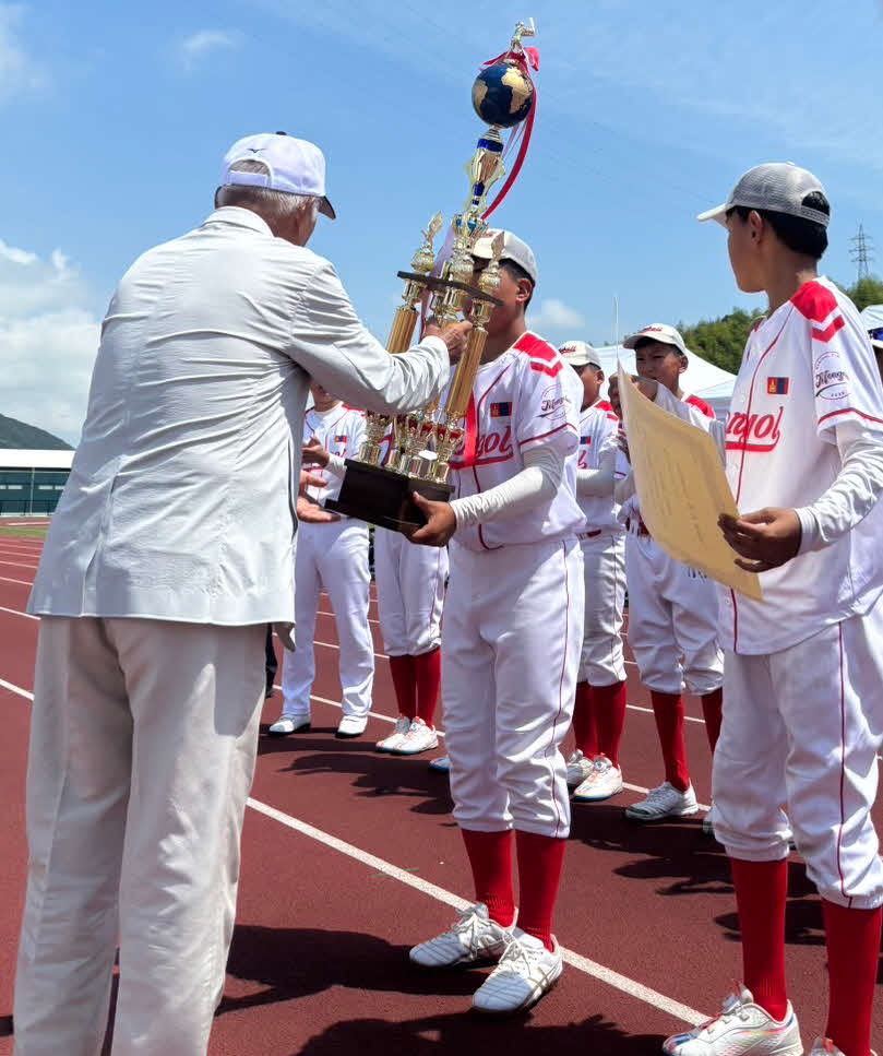 モンゴルのチームはティーボールのアジア大会を制し、アジアティーボール連盟の河内志郎副会長からトロフィーを受け取る（大会関係者提供）