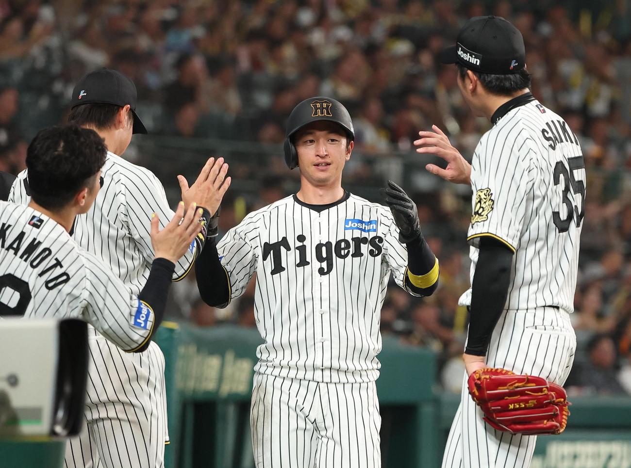 阪神対巨人　3回裏阪神1死一、二塁、森下の先制適時打で生還した近本（中央）は才木（左）らナインとハイタッチする（撮影・上田博志）