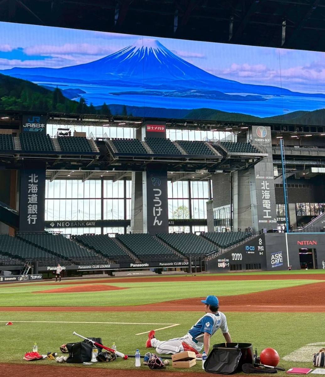 羊蹄山が映る大型ビジョンの前でストレッチする日本ハム伊藤