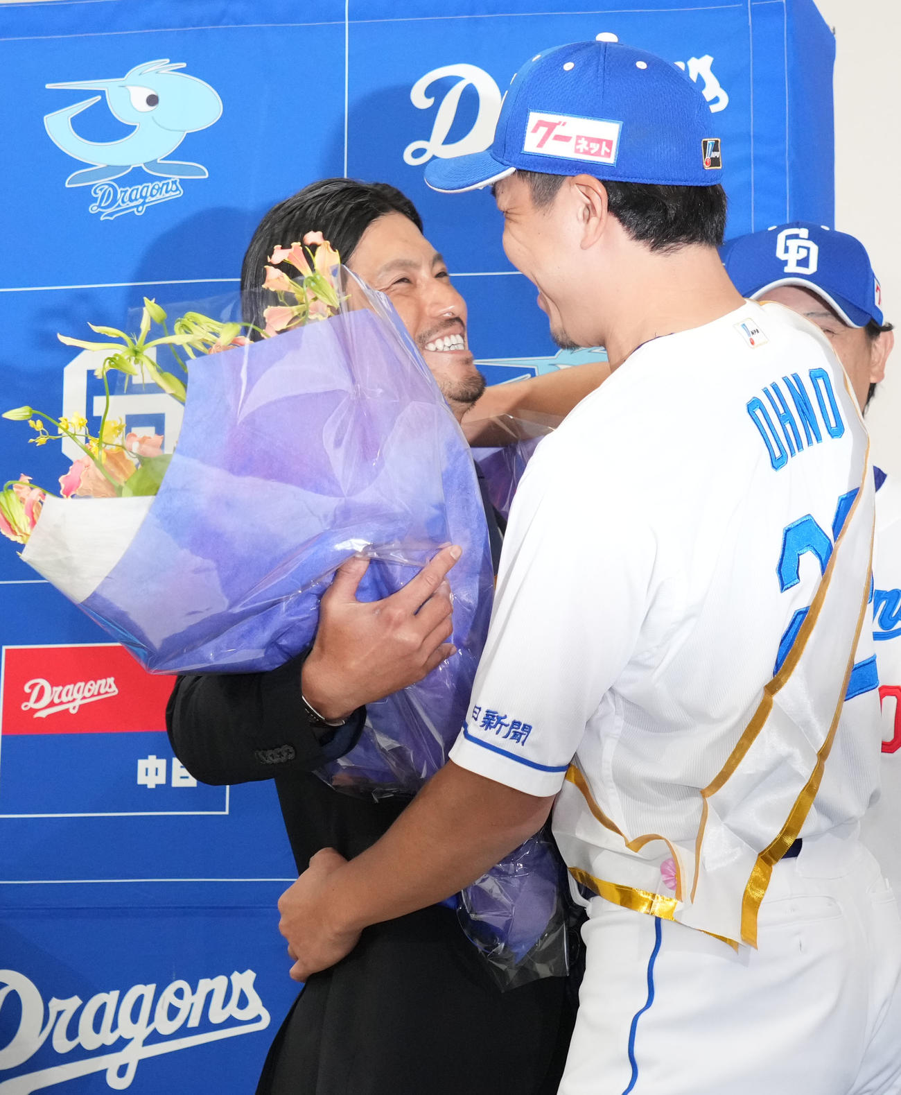 会見後、祖父江（左）は大野から花束を受け取りハグを交わす（撮影・森本幸一）