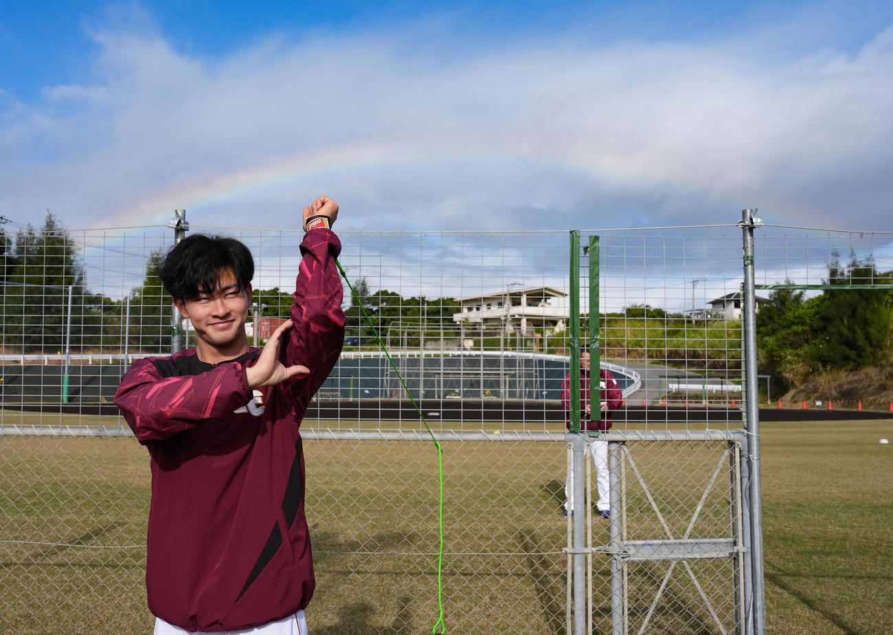 楽天沖縄・金武春季キャンプ　笑顔で体を動かす古謝樹。後ろには大きな虹がかかった（2025年2月撮影）