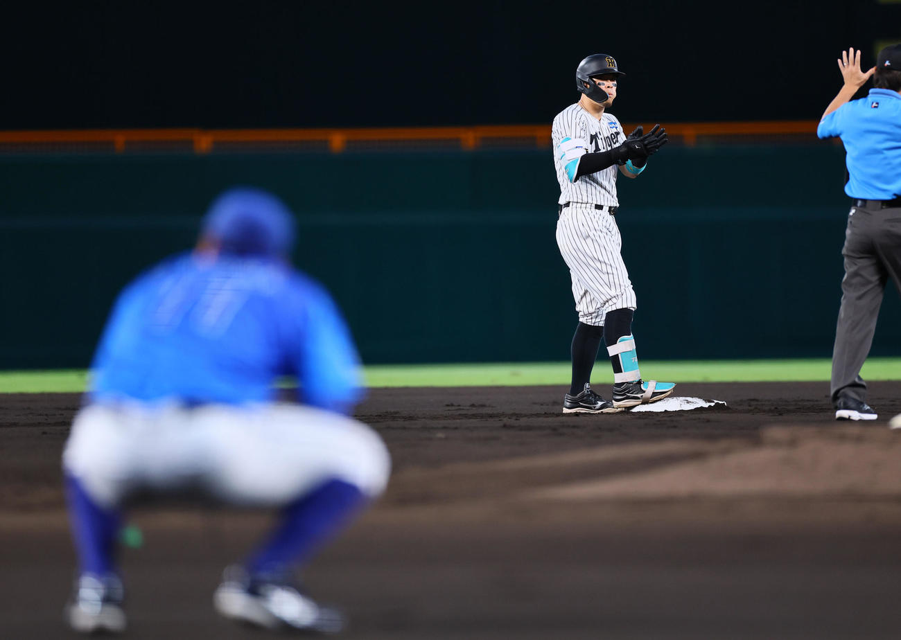 阪神対DeNA 1回裏阪神2死二塁、右翼手蝦名が打球を見失い、適時二塁打を放ち手をたたく佐藤輝。手前は東（撮影・藤尾明華）
