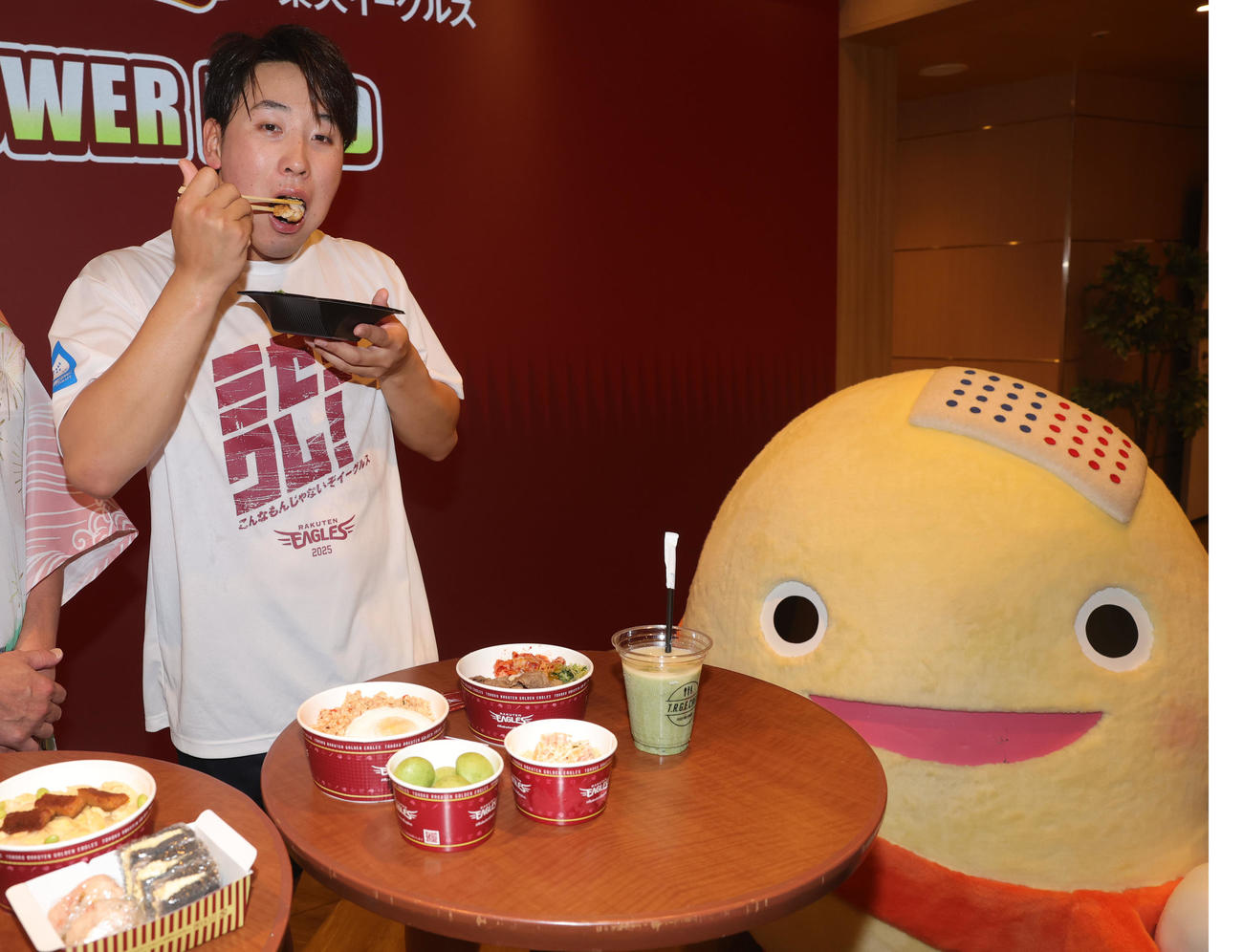 石川県七尾市の食材を使用した「NANAO POWER FOOD」の販売を記念して、試食する楽天藤平。右は和倉温泉のキャラクターわくたまくん（撮影・野上伸悟）