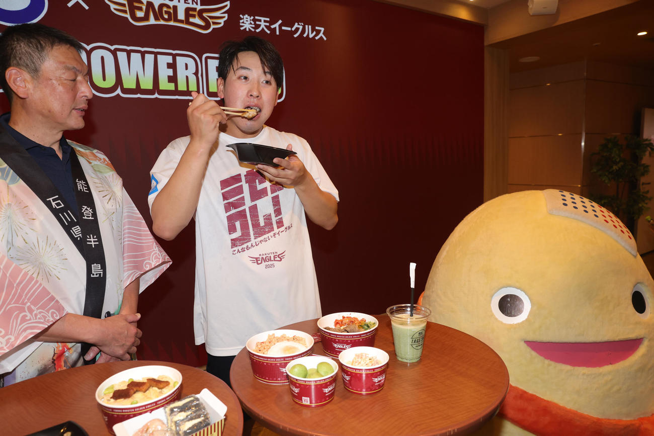 石川県七尾市の食材を使用した「NANAO POWER FOOD」の販売を記念して、試食する楽天藤平。右は和倉温泉のキャラクターわくたまくん（撮影・野上伸悟）