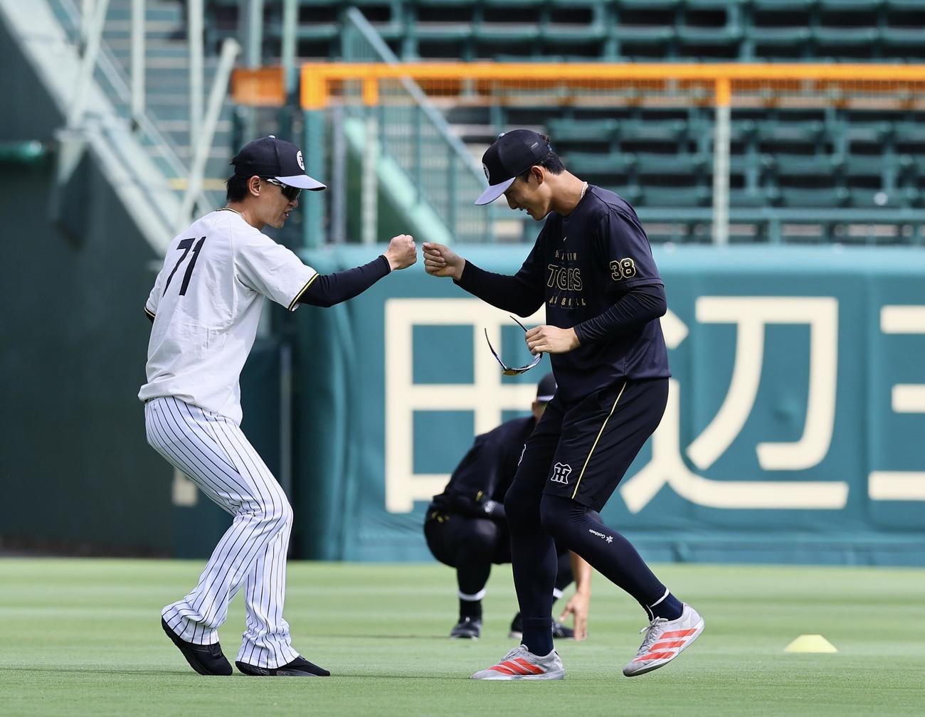 阪神対DeNA 1軍に合流し、上本コーチ（左）とタッチを交わす阪神小幡（撮影・藤尾明華）