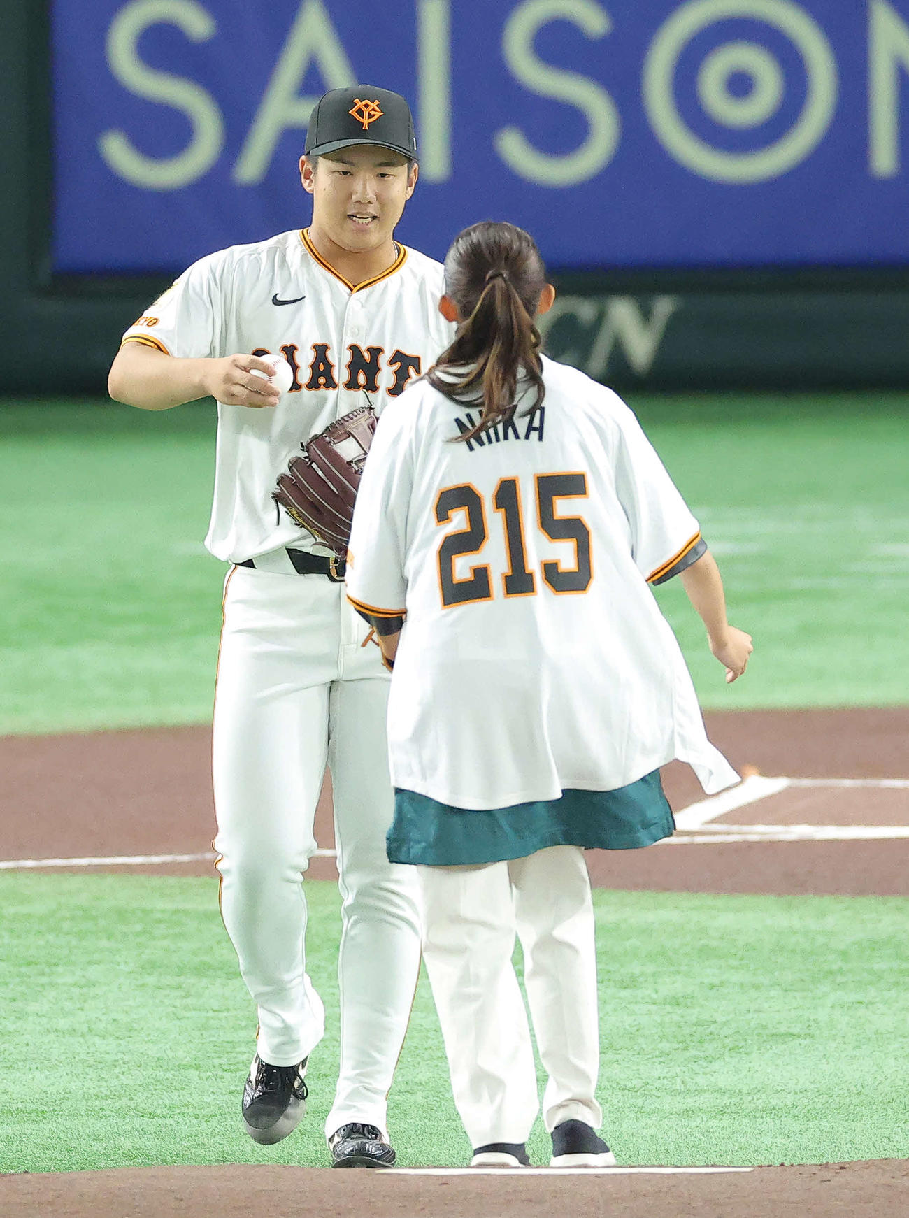 巨人対広島　試合前、ファーストピッチセレモニーを務めた五十嵐にいか日本テレビアナウンサー（手前）に記念球を渡す巨人石塚（撮影・河田真司）