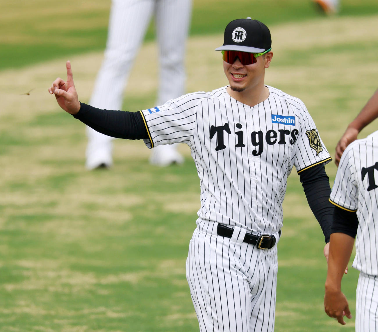 練習中、笑顔で人さし指を立てる佐藤輝（撮影・加藤哉）