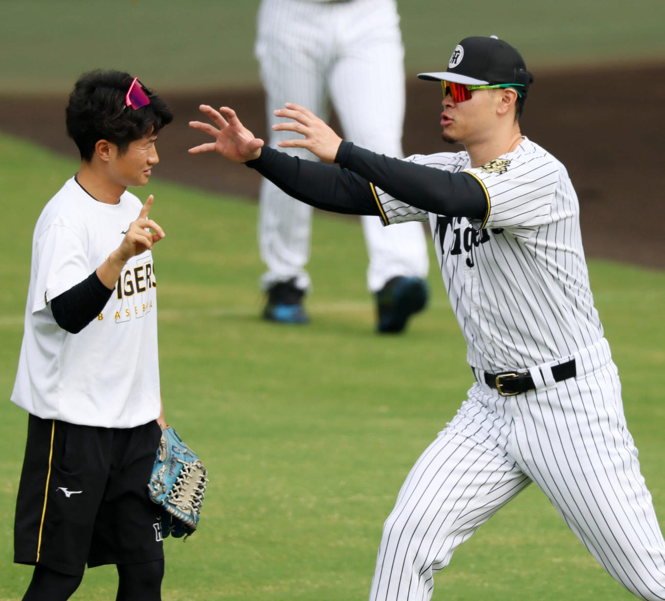 練習開始前、目の前を飛ぶトンボを捕まえようとした佐藤輝（右）だが手を伸ばした先は橘通訳でした（撮影・加藤哉）