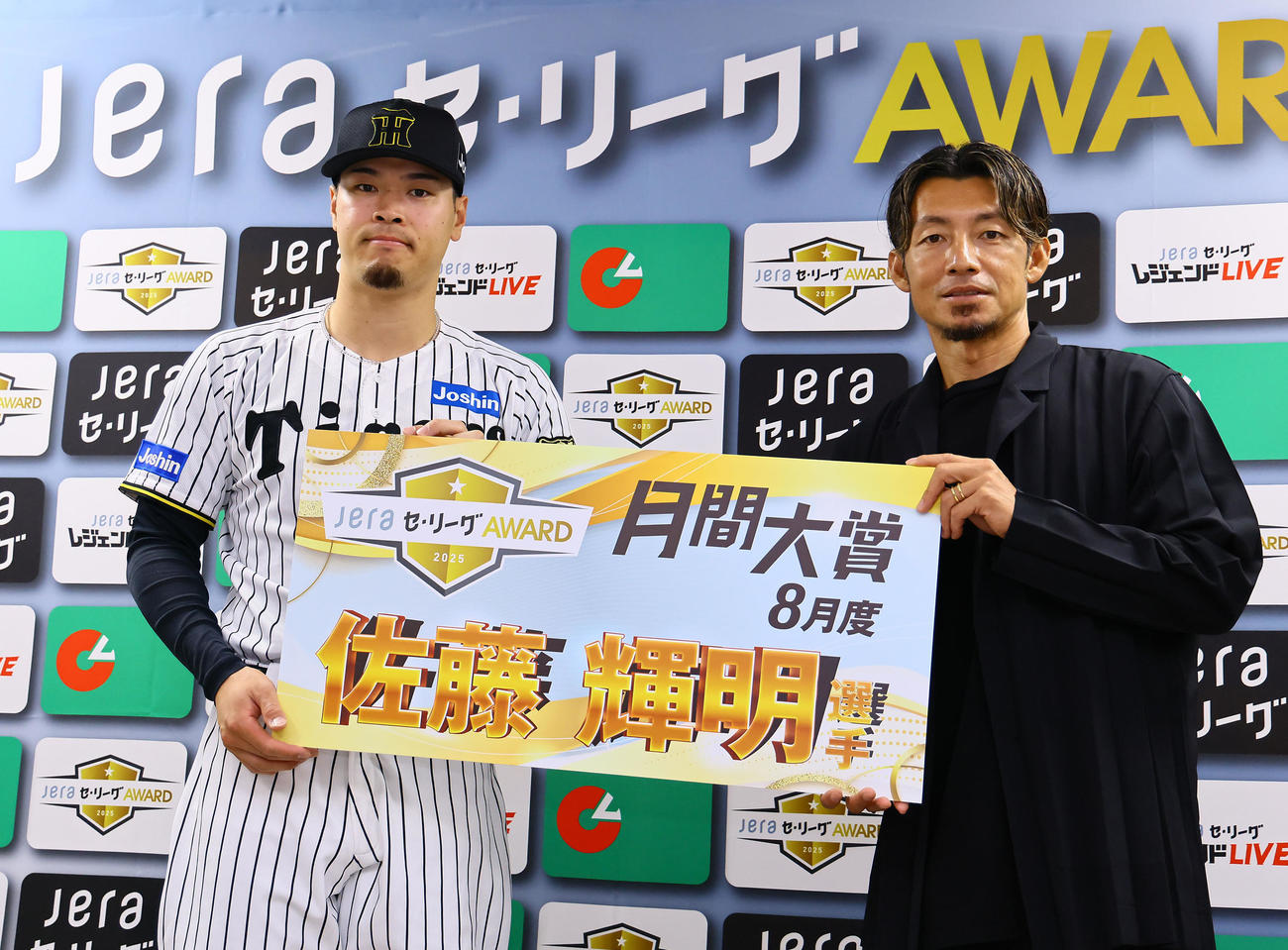 「JERAセ・リーグAWARD8月度月間大賞」を受賞し、鳥谷敬氏から渡された記念ボード手に写真に納まる阪神佐藤輝（撮影・藤尾明華）