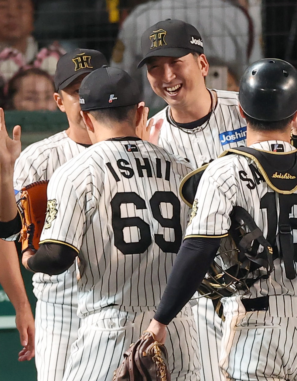 阪神対中日　藤川監督（中央）は48イニング無失点の球団記録を達成した石井を笑顔で出迎える（撮影・上田博志）