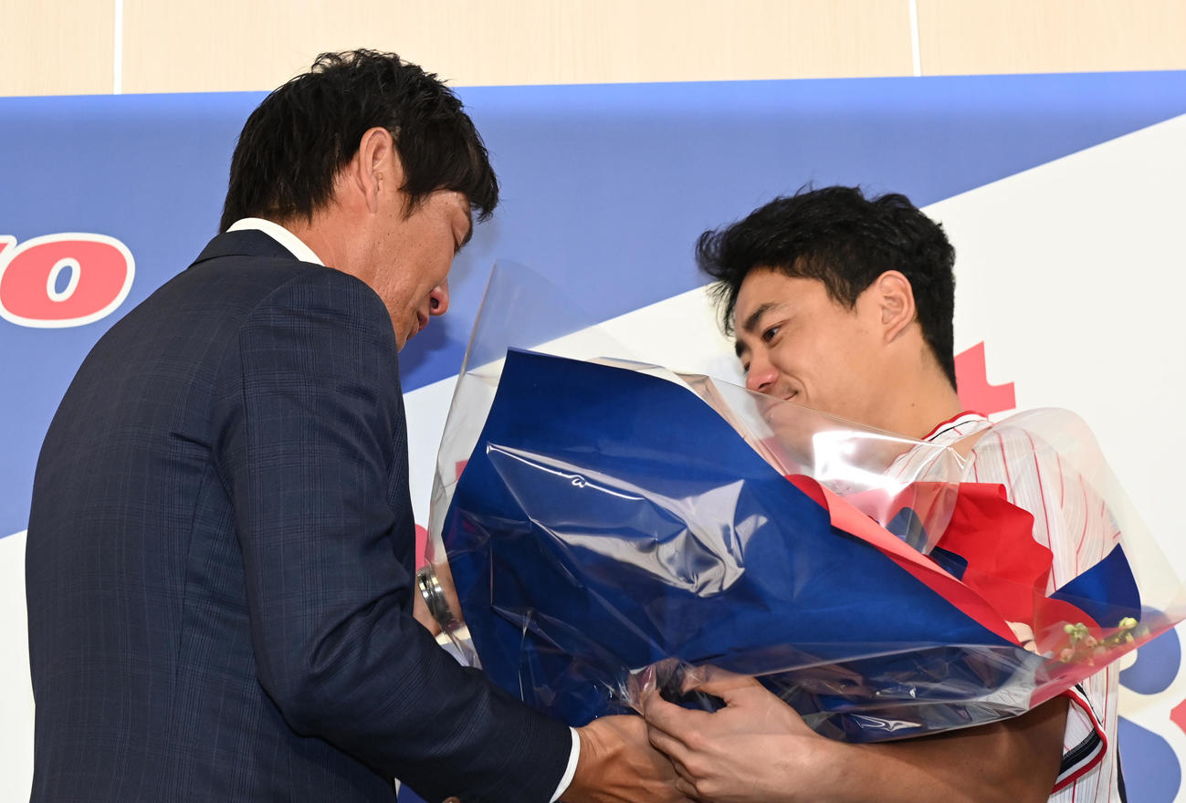 会見場に姿をみせたヤクルト中村悠（右）から花束を受け取る川端（撮影・清水貴仁）