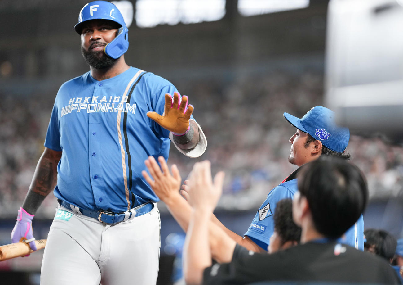 ロッテ対日本ハム　7回表日本ハム1死一、三塁、右犠飛を放ったレイエス（左）を迎える伊藤（撮影・鈴木みどり）