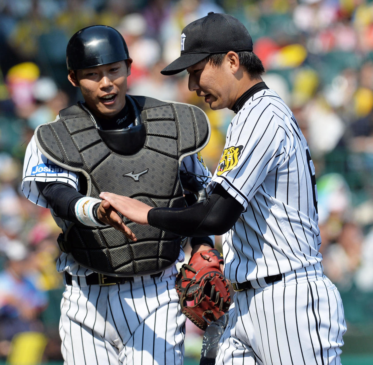 ピンチを切り抜け笑顔でタッチの岩崎優（右）と原口文仁（2016年5月21日撮影）