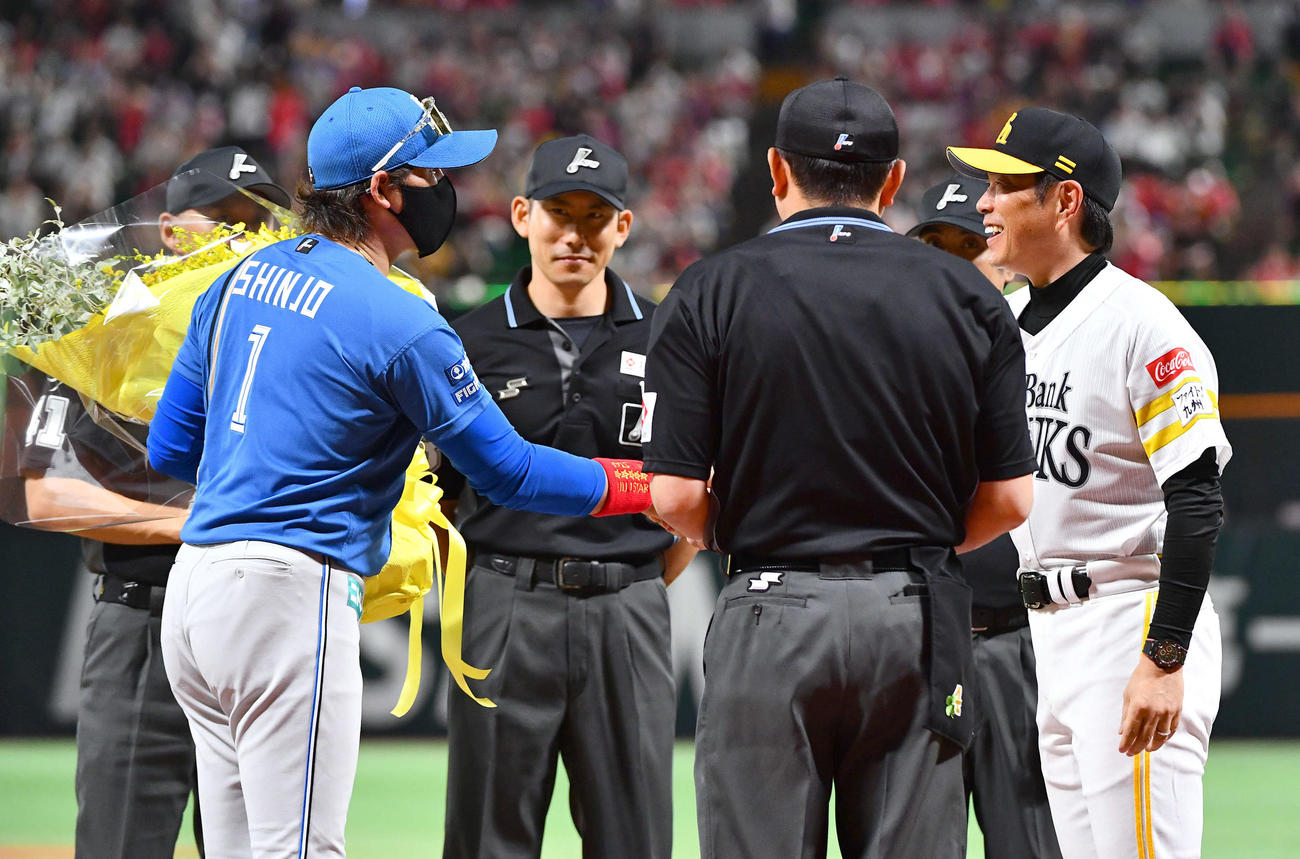 ソフトバンク対日本ハム　試合前のメンバー表交換でリーグ優勝したソフトバンク小久保監督（右）に黄色の花束を用意した日本ハム新庄監督（撮影・岩下翔太）