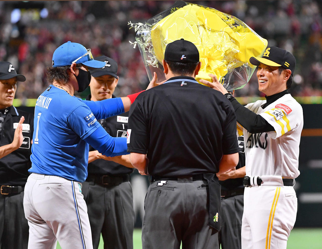 ソフトバンク対日本ハム　試合前のメンバー表交換で日本ハム新庄監督（左）からリーグ優勝のお祝いに黄色の花束を贈られ、笑顔を見せるソフトバンク小久保監督（撮影・岩下翔太）