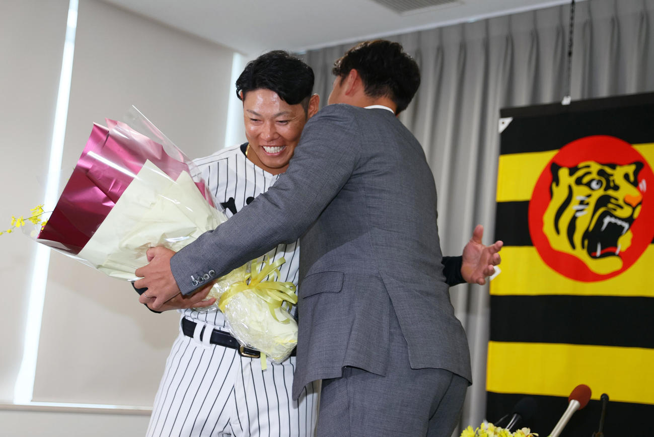 サプライズで登場し、阪神原口（左）に花束を渡す秋山BA（撮影・上山淳一）