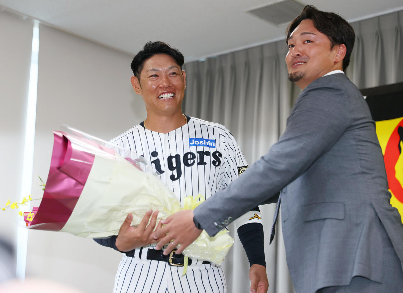 サプライズで登場し、阪神原口（左）に花束を渡す秋山BA（撮影・上山淳一）