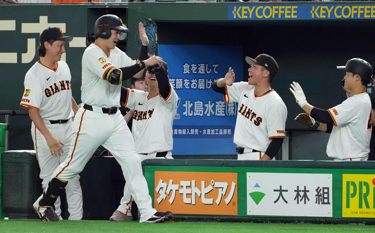 巨人対中日　6回裏巨人無死一塁、四球を選び出塁した泉口は、代走を出されベンチに戻りナインとハイタッチを交わす（撮影・たえ見朱実）