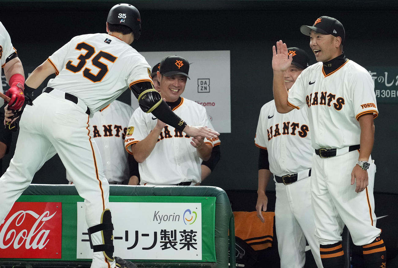 巨人対中日　6回裏巨人無死一塁、四球を選び出塁した泉口は、代走を出されベンチに戻り阿部監督とハイタッチを交わす（撮影・たえ見朱実）